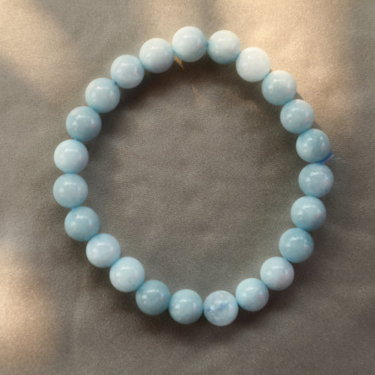 A collection of raw Aquamarine crystals displaying varying shades of translucent blue, symbolizing tranquility and clarity. The stones' natural formations reflect their soothing energy and association with the sea.