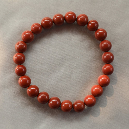 Polished red jasper crystal with deep earthy tones, symbolizing grounding, strength, and stability—ideal for energy work, meditation, or chakra healing.