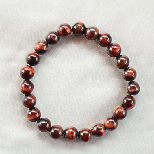 Polished Red Tiger’s Eye crystal with rich reddish-brown bands and silky chatoyancy, symbolizing motivation, confidence, and grounded energy.