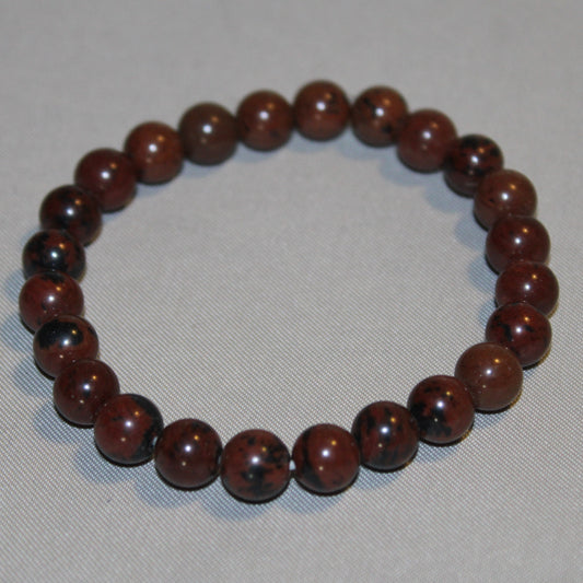 Mahogany Obsidian crystal with deep red and black tones, polished to a smooth finish, symbolizing grounding, protection, and emotional healing.