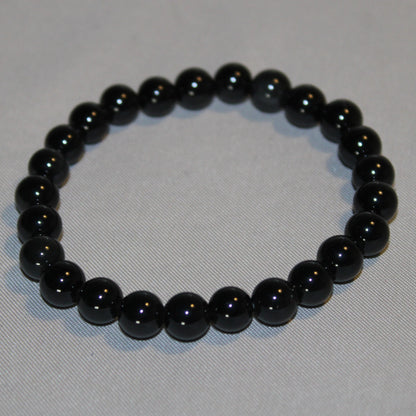 A polished Black Obsidian crystal with a deep, glossy black surface, reflecting light subtly. Known for its grounding and protective properties, this volcanic glass is often used in spiritual practices for energy cleansing and emotional healing. 