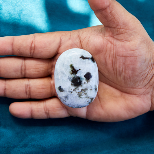 Moonstone crystal with a soft, iridescent glow reflecting shades of white, blue, and peach, symbolizing intuition, emotional balance, and new beginnings.
